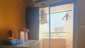 A small, compact room with a sliding glass door leading to a balcony. - Buddy Mansion (Bangkok)