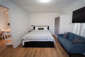 Ein Schlafzimmer mit einem Bett, einem blauen Sofa, einem Schreibtisch und einem Sessel.