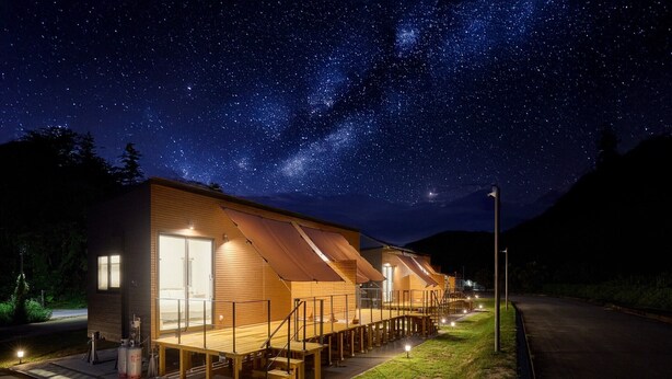 A row of wooden cabins with a starry night sky above, connected by a covered walkway. - Yambaru Experience Hotel Nunganiku (Higashi)