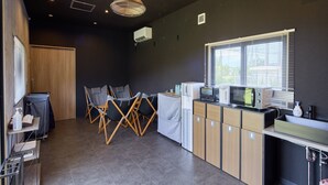 A modern kitchen with a dining area, equipped with a microwave, toaster, and a sink. - Yambaru Experience Hotel Nunganiku (Higashi)