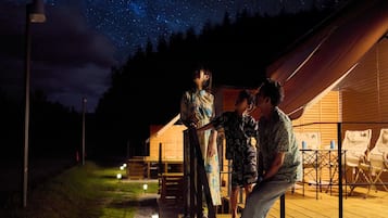 Een sterrenhemel boven een houten chalet met een overdekt terras.