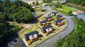 A coastal resort with multiple bungalow-style accommodations, a road leading to the beach, and a view of the ocean. - Yambaru Experience Hotel Nunganiku (Higashi)