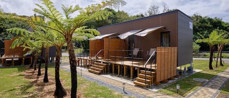 Un edificio moderno con terraza, asientos al aire libre y un sendero.