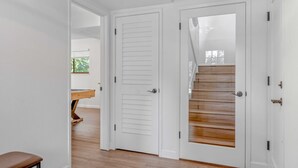 A hallway with white doors, a wooden bench, and a staircase with wooden steps.