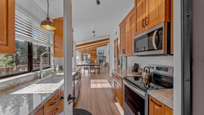 A modern kitchen with wooden cabinets, stainless steel appliances, and a granite countertop.