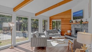 A spacious living room with large windows, a fireplace, and a modern sofa set.