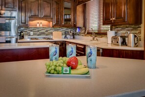 A kitchen counter with a fruit and drink display. - Luxury Lakeside Escape with Private Pool, Kayaks and Billiards – Masters Retreat (Evans)