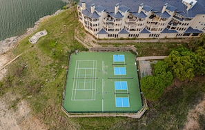 An aerial view of a tennis court with a building adjacent to it. - Sunset & Lakeview from Castle Turret on The Island (Lago Vista)