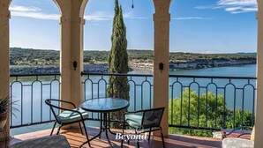 A balcony with a view of a lake, surrounded by trees and hills. - Sunset & Lakeview from Castle Turret on The Island (Lago Vista)