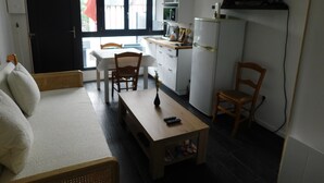 A compact living space with a kitchenette, a dining area, and a sofa. - Short-term furnished studio rental (n° 3) (Le Trait)