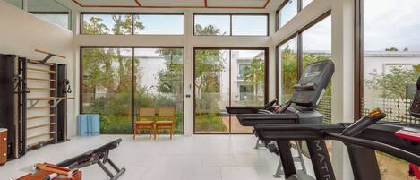 A modern gym with treadmills, a rowing machine, and exercise equipment.