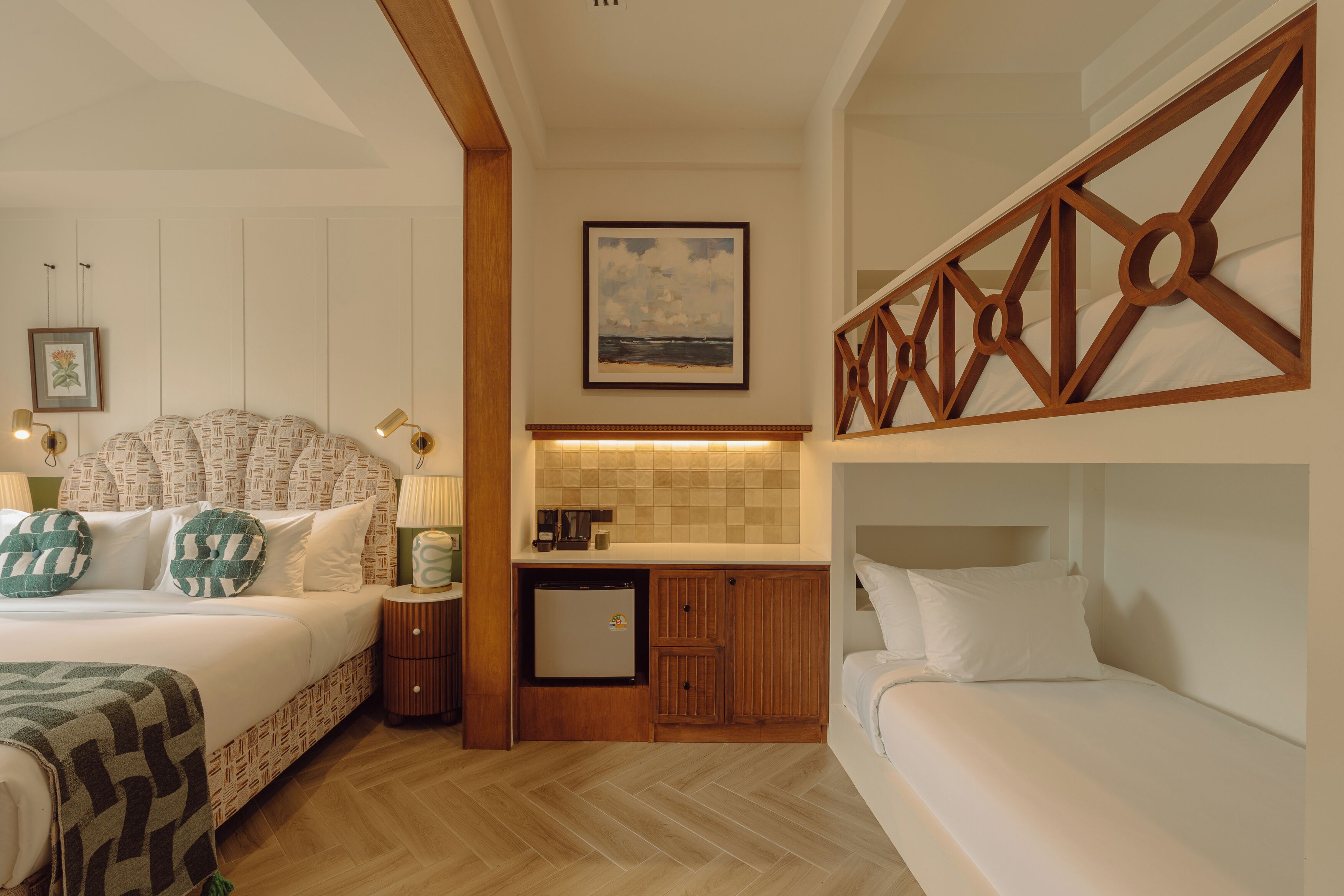 A bedroom with a bed, a small kitchenette, a wooden headboard, and a wall-mounted picture.
