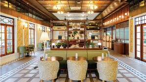 A hotel lobby with a checkered floor, green seating, and a central display of suitcases. - Sugar Marina Resort - LAGOON - Villas, Naiyang Beach (Sa Khu)