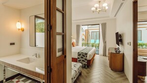 Une chambre d’hôtel moderne dotée d’une grande salle de bain, d’un lit avec une couvre-lit à motifs, d’une table de chevet en bois et d’une vue sur l’extérieur.