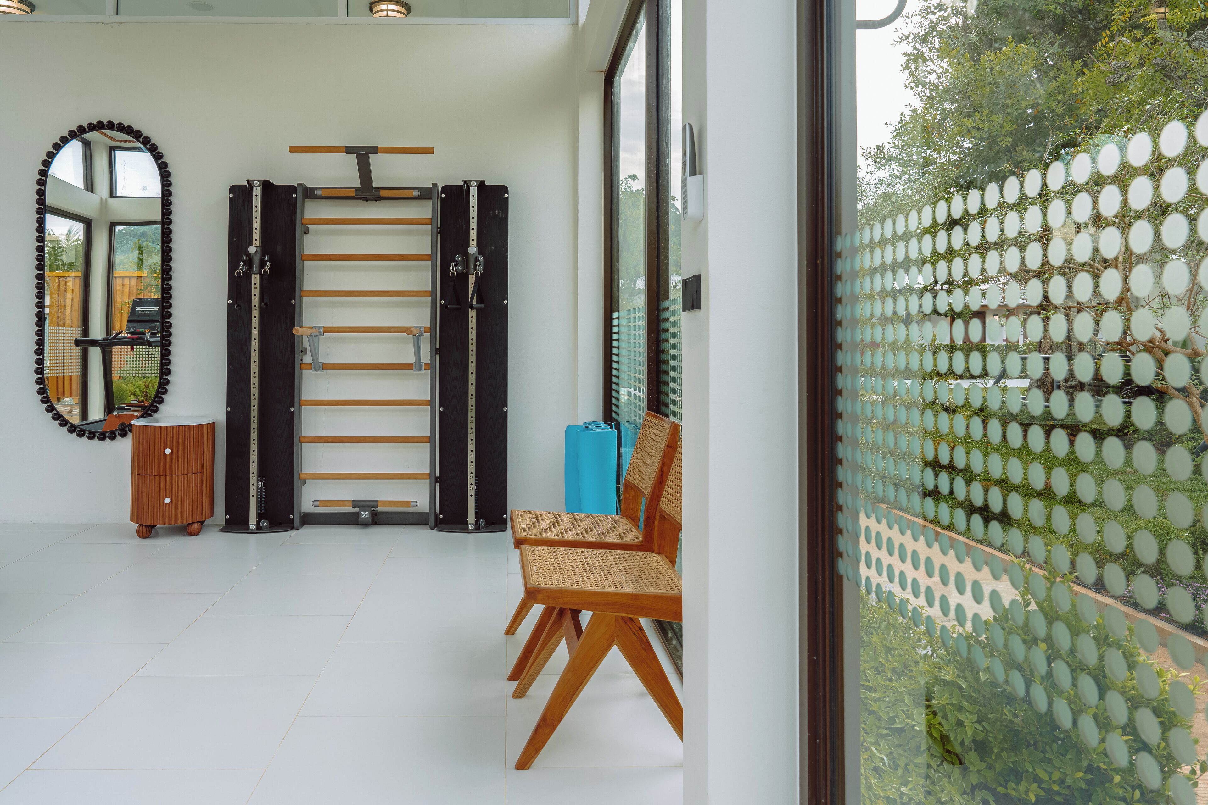 Una habitación moderna con una barra para dominadas, una silla de madera y un espejo.