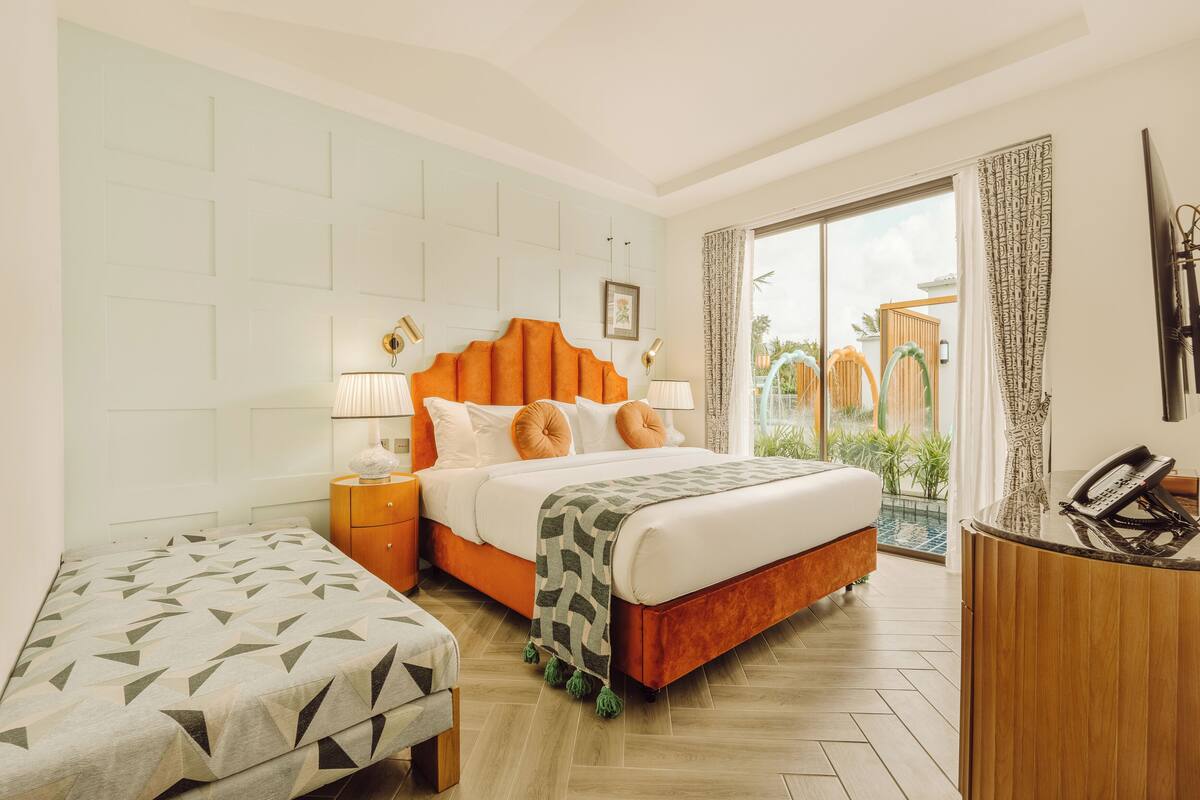 Une chambre d’hôtel avec un lit, une table de chevet, un bureau et une vue sur l’extérieur.