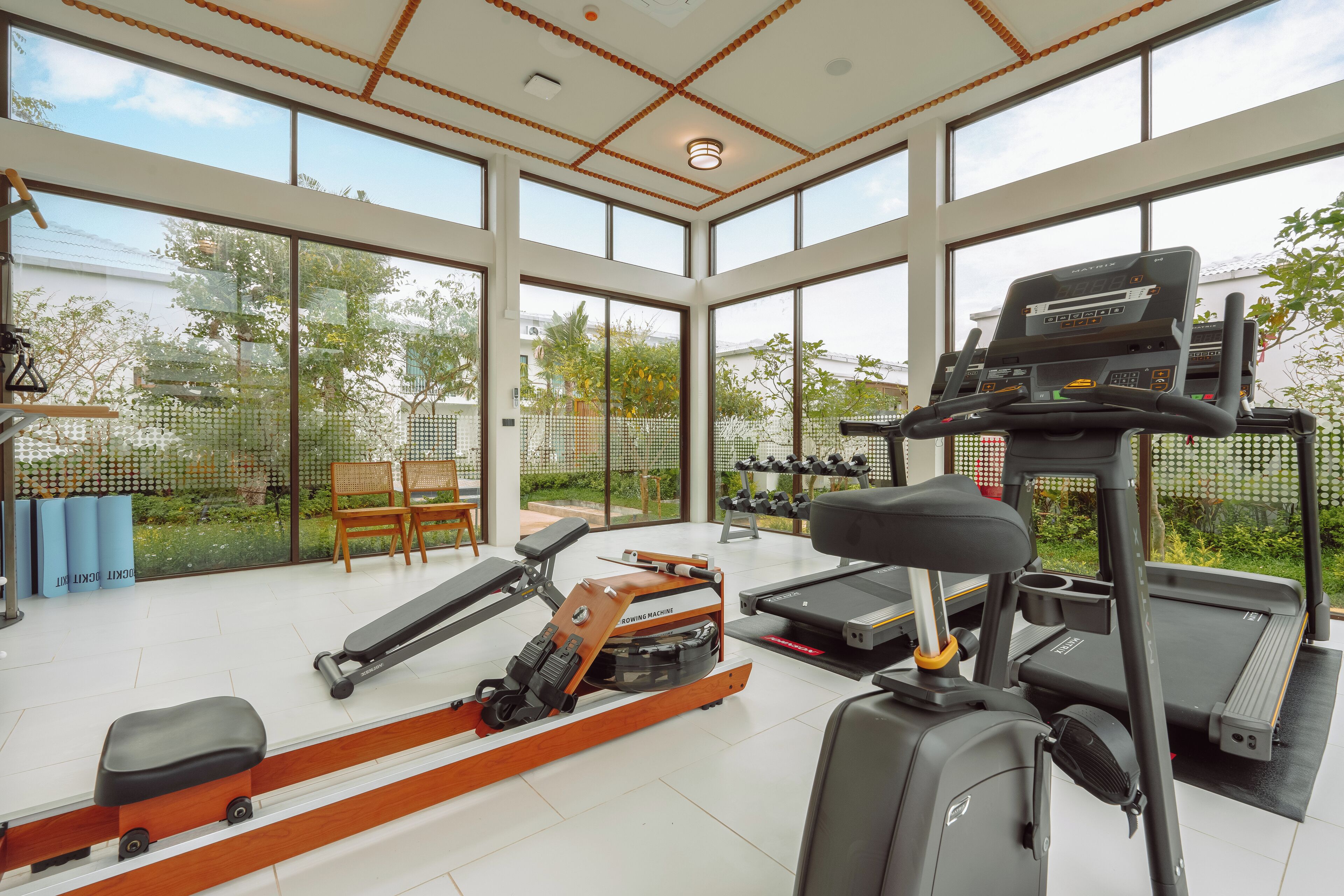 A gym with cardio equipment, large windows, and outdoor views.