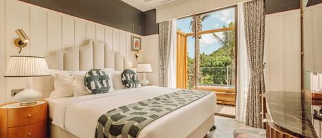 Quarto de hotel moderno com uma cama grande, uma mesinha de cabeceira de madeira, bancada de banheiro em mármore e uma varanda com vista para o verde.