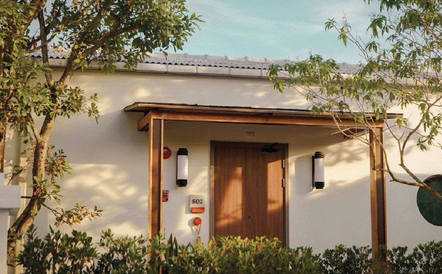 A building with a wooden door, a sign with 'SOZ' on it, and two wall-mounted lights.
