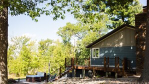 A cabin with a deck, hot tub, and a stone foundation.