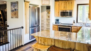 A kitchen with wooden cabinets, a stainless steel refrigerator, a microwave, and a granite countertop.