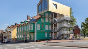 Un edificio con fachada verde y un diseño arquitectónico distintivo, que alberga un museo y una escalera que conduce a un nivel superior.