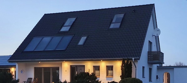 Ein zweistöckiges Haus mit einem geneigten Dach, Dachfenstern und einem kleinen Balkon.