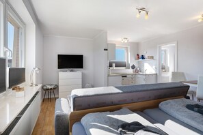 A modern hotel room with a bed, a TV, a desk, and a kitchenette. - Studio Apartment 'Ferienwohnung Friesenkoje' with Private Terrace, Shared Garden and Wi-Fi (Nordstrand)