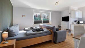 Ein modernes Schlafzimmer mit Bett, Nachttisch, Lampe und Blick ins Freie.