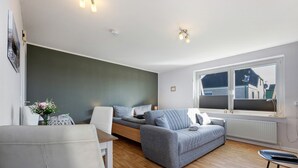 Ein modernes Wohnzimmer mit einer Couch, einem Esstisch und einem Fenster mit Blick auf Gebäude.