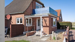 A brick house with a sign reading 'Haus am Meer,' a small porch, and a solar panel on the roof. - Apartment 'Ferienwohnung Kapitänskajüte' with Private Terrace, Shared Garden and Wi-Fi (Nordstrand)