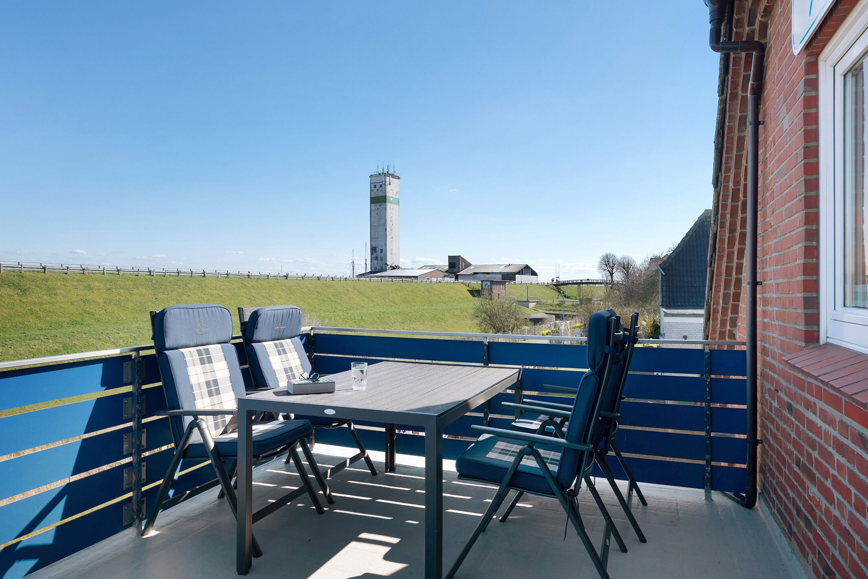 A balcony with a table and chairs, a view of a tower, and a brick building.