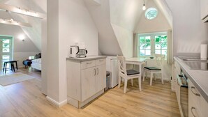 Eine moderne Küche mit Essbereich, einem kleinen Kühlschrank und einer Kaffeemaschine.