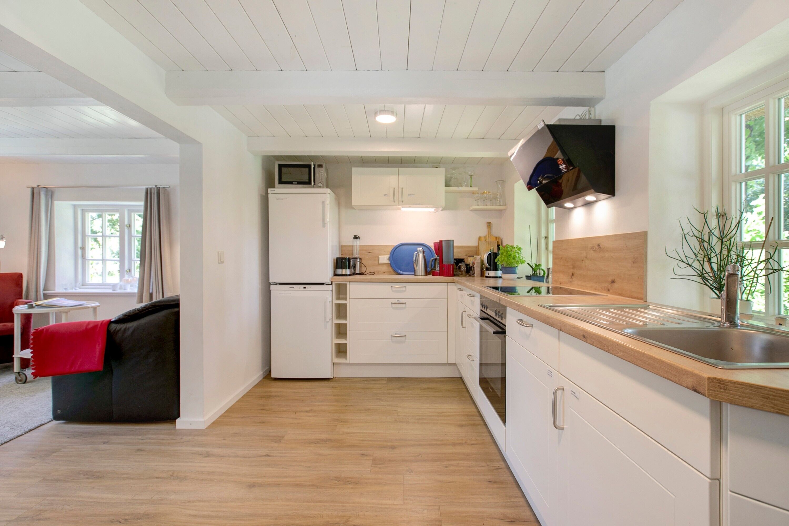 A compact kitchen with white cabinets, a microwave, a sink, and a wooden countertop.