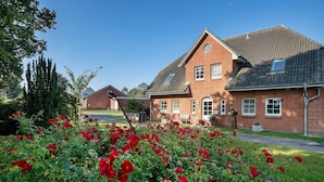 A brick building with a gabled roof, a small window, and a door. - Apartment 'Ferienwohnung Andresen Högel' with Shared Terrace, Shared Garden and Wi-Fi (Högel)