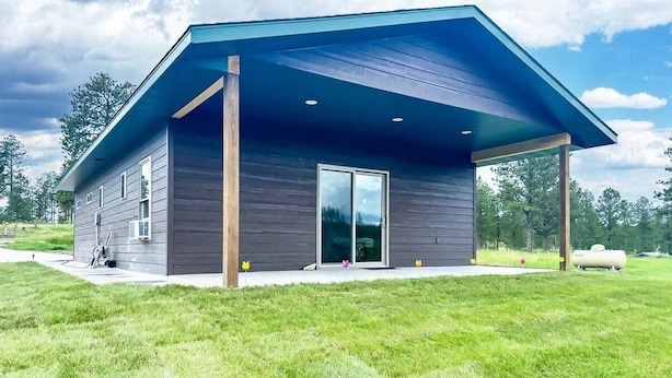 Un bâtiment moderne doté d’un toit plat, de grandes portes vitrées et d’un patio couvert.