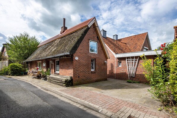 A brick house with a sloped roof, a visible chimney, and a small porch area.