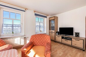 Una sala de estar con sofá, televisor y mueble de madera.