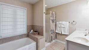 A bathroom with a bathtub, a shower curtain, a sink, and a towel rack. - Greene Hills Vista Cottage (Stanardsville)