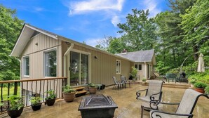 A covered patio with outdoor furniture, potted plants, and a stone fireplace. - Greene Hills Vista Cottage (Stanardsville)