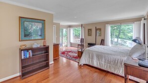 A bedroom with a bed, a bookshelf, a desk, and a window with a view of trees. - Greene Hills Vista Cottage (Stanardsville)
