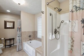 A bathroom with a bathtub, shower, toilet, and a mirror.