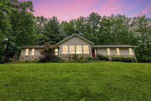 A two-story house with a stone foundation, large windows, and a well-maintained lawn.