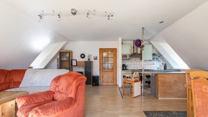Un espai habitable d'estil loft amb un sostre alt, una zona de cuina i una zona de seients amb un sofà i una taula.