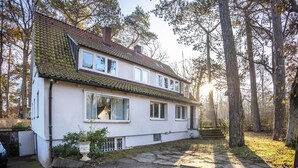 A two-story house with a sloped roof, large windows, and a stone pathway leading to the entrance. - Holiday Home 'Sandstrand' with Private Terrace, Garden, and Wi-Fi (Timmendorfer Strand)