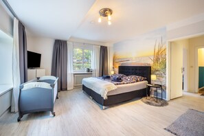 Une chambre à coucher avec un lit, un bureau, une chaise, une télévision et une fenêtre.