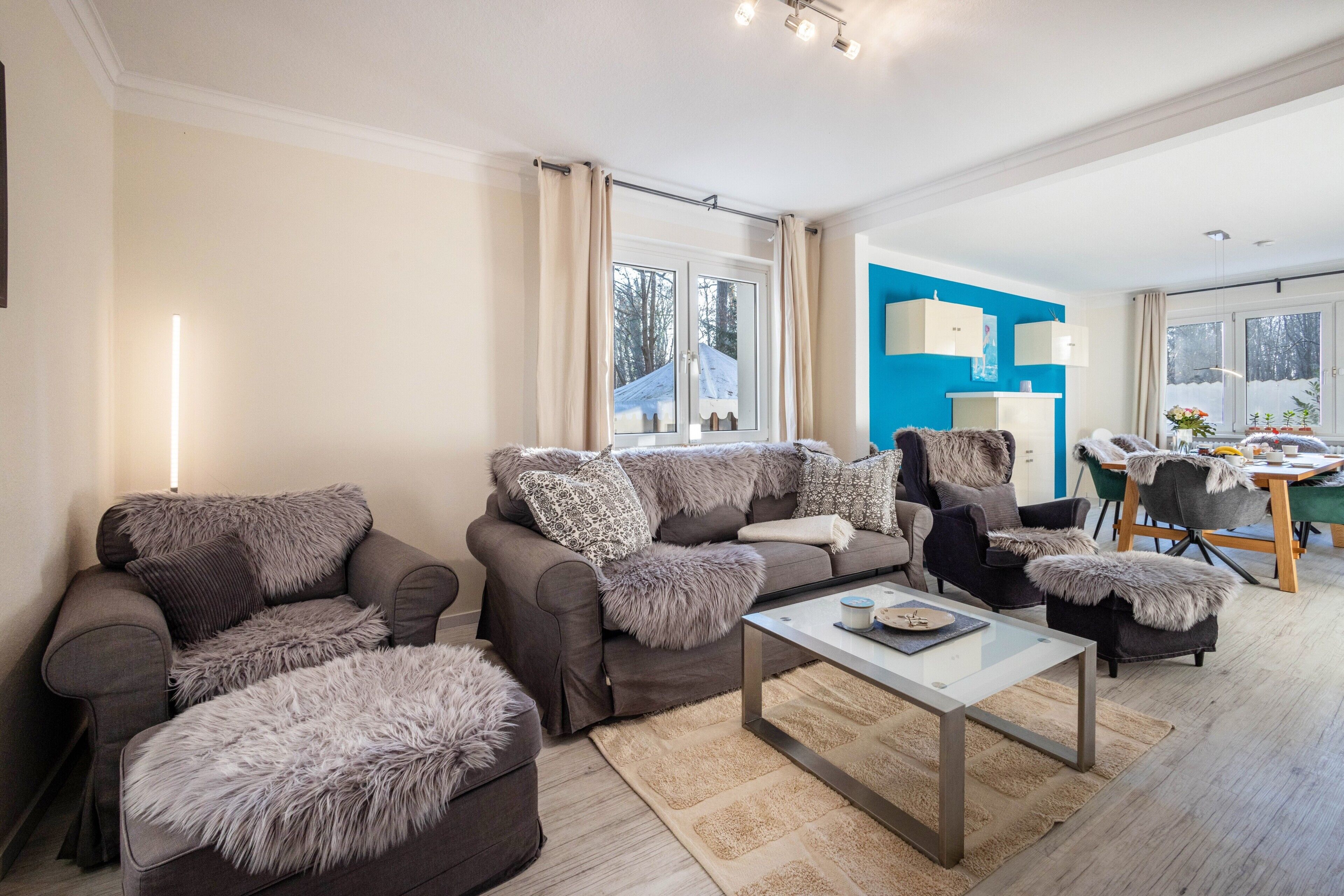 Een moderne woonkamer met een zithoek, een salontafel en een eethoek met stoelen en een tafel.