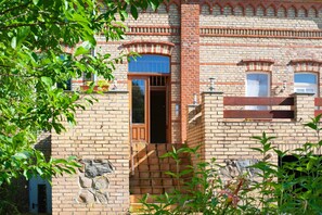 A brick building with a wooden door, arched windows, and stone accents.