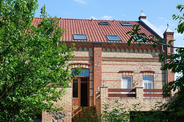 A brick building with a red-tiled roof, arched windows, and a visible entrance.