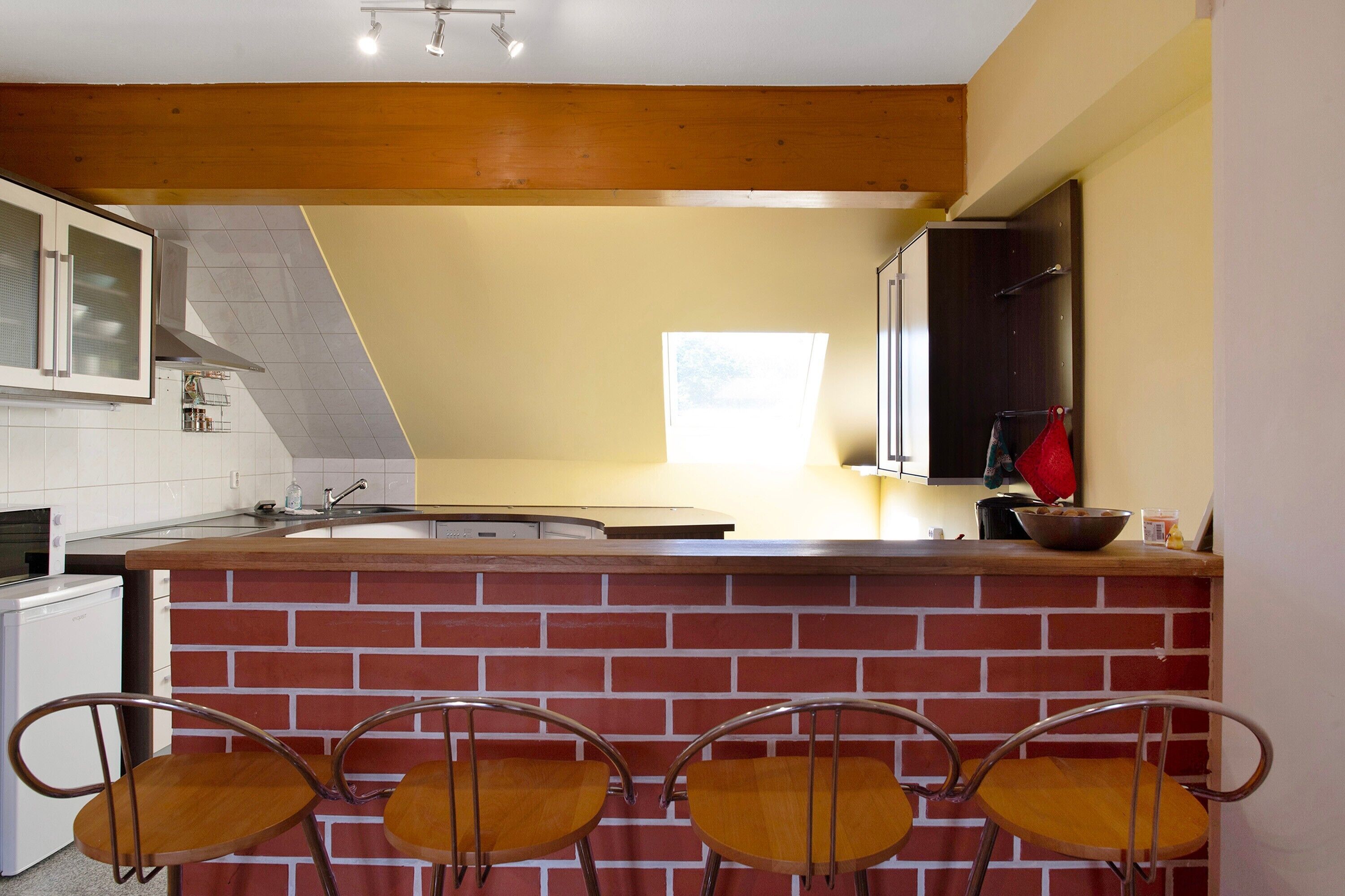 A kitchen with a brick counter, white cabinets, and a window.